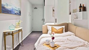 Un dormitorio con cama, mesita de noche y un cuadro en la pared.