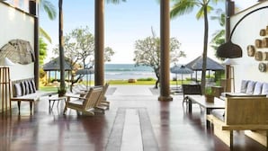 A spacious indoor area with wooden flooring, seating arrangements, and a view of the ocean. - Villa Melissa (Bali)