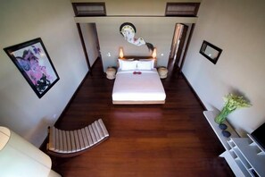 A bedroom with a bed, bedside tables, a chair, and a small table with a vase. - Villa Melissa (Bali)