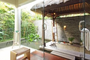 A glass-enclosed spa area with a wooden bench, a ladder, and a stone wall. - Villa Melissa (Bali)