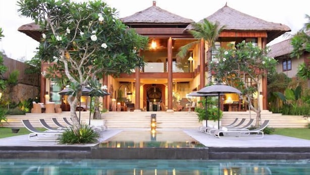 A resort with a swimming pool, lounge chairs, and a large building with a thatched roof. - Villa Melissa (Bali)