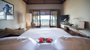 A hotel room with a large bed, a hammock, a TV, and a view of the ocean. - Villa Melissa (Bali)
