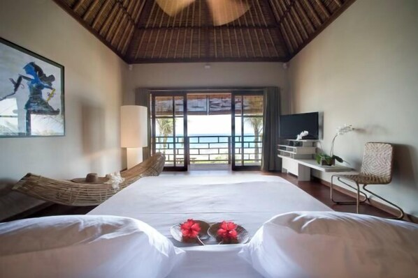 A hotel room with a large bed, a hammock, a TV, and a view of the ocean. - Villa Melissa (Bali)