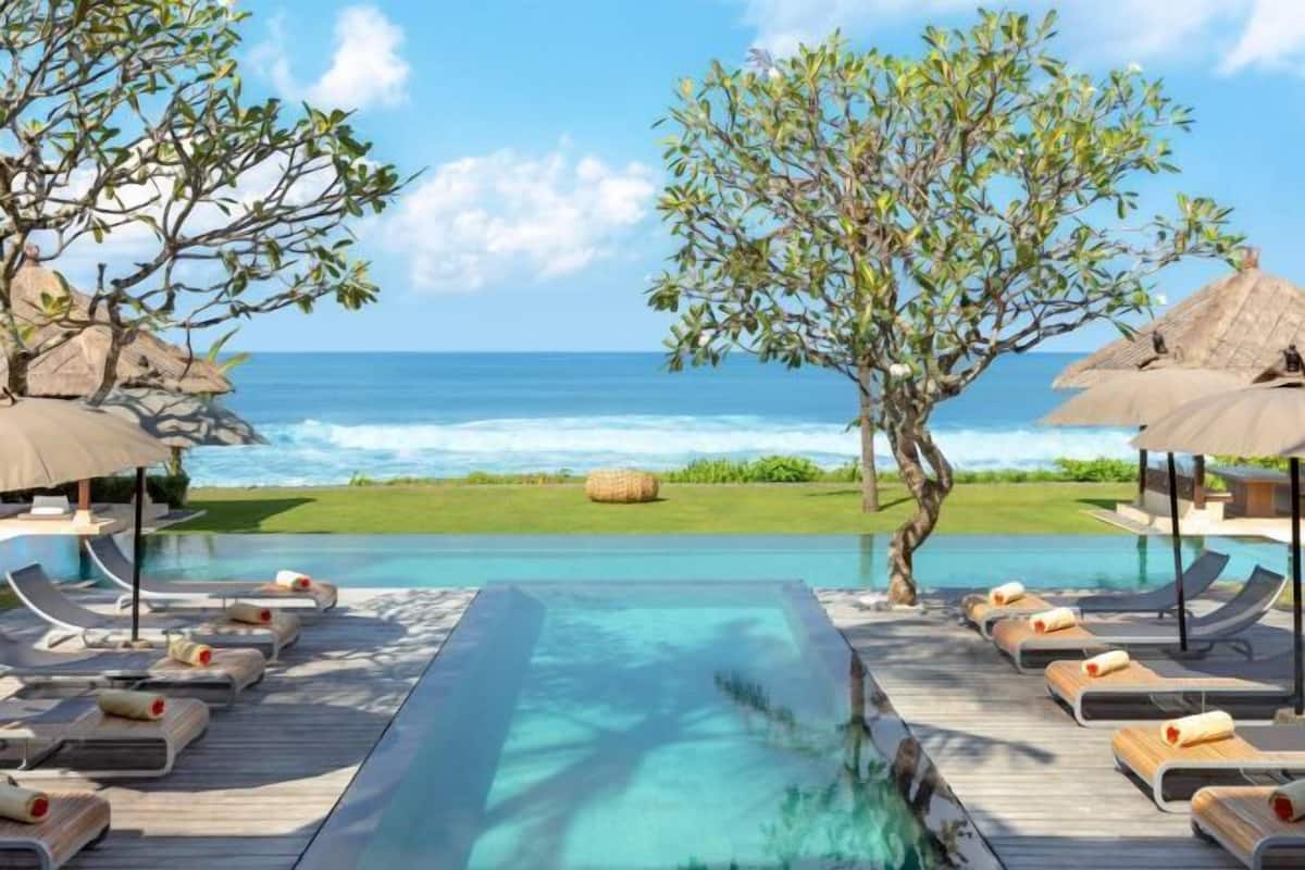 A poolside area with lounge chairs and a view of the ocean.