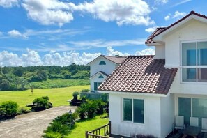 A two-story building with a tiled roof, a visible entrance, and a paved driveway. - Tebaz (Jeju)
