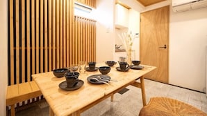 A dining table with black bowls and chopsticks, a woven chair, and a wooden partition.