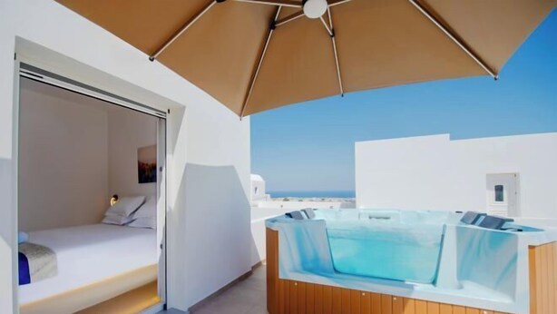 Een moderne kamer met een bed, een jacuzzi en uitzicht op zee.