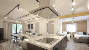 Eine moderne Küche mit Kochinsel, Essbereich und einem Schlafzimmer mit großem Bett und Fenster.