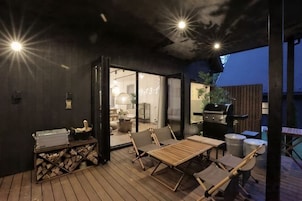 Terraza exterior con una parrilla, asientos y vistas al interior.
