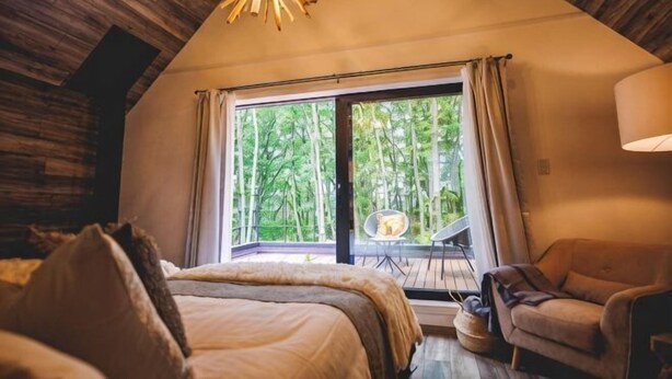 Ein Schlafzimmer mit großem Fenster, einem Bett, einem Sessel und einer Hängelampe.