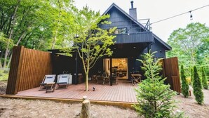 Ein modernes Haus mit einer Terrasse, Sitzgelegenheiten im Freien und einem großen Fenster.
