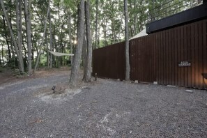 A gravel path leading to a wooden fence with a sign, surrounded by trees. - [TV] Luxury adult secret base villa 120 ㎡ Sauna, stone bath, bonfire, BBQ [Mori building] (Miyota)
