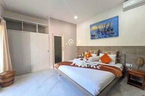 A bedroom with a bed, a nightstand, a painting, a wardrobe, and a window. - Enno Villa Sanur (Bali)