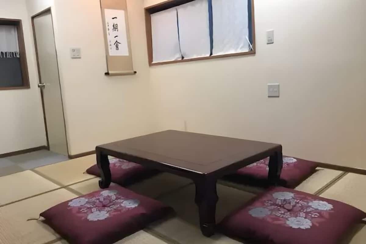 Una habitació japonesa tradicional amb paviment de tatami, una taula de fusta baixa i coixins florals.