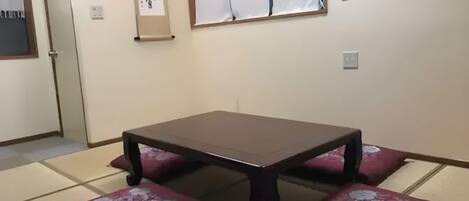 A traditional Japanese room with tatami flooring, a low table with cushions, and a shoji screen.
