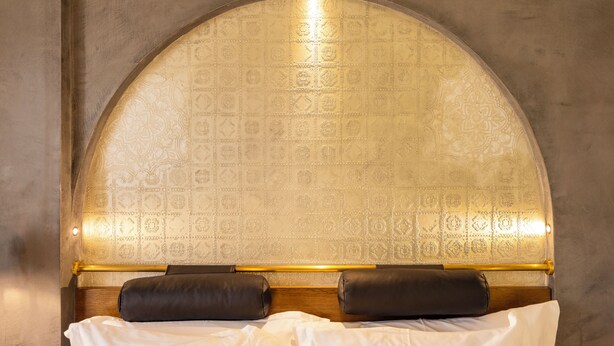 A bed with a headboard featuring an arched design and a patterned wallpaper. - Onomo Ain Sebaa (Casablanca)