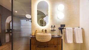 A modern bathroom with a wooden vanity, a round mirror, and two wall-mounted lights. - Onomo Ain Sebaa (Casablanca)