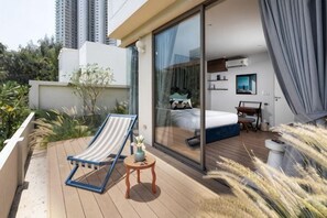 A balcony with a lounge chair, a small table, and a bed visible through a glass door. - Prime Beach House No. V7 (Sattahip)