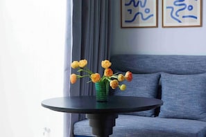 A round table with a vase of flowers in front of a sofa. - Prime Beach House No. V7 (Sattahip)