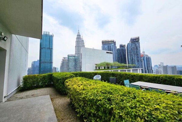 A rooftop terrace with a view of a city skyline, including modern buildings and a distinctive skyscraper.