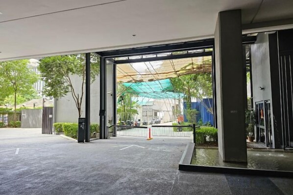 A hotel entrance with a covered outdoor area, a parking lot, and a building facade.