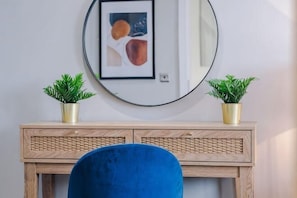A room with a wooden console table, two potted plants, a blue chair, and a round mirror on the wall. - Host & Stay The Baltic Penthouse 2 (Liverpool)