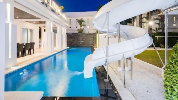 A swimming pool with a slide, a covered outdoor area, and a building with 'MYLIND' signage. - Modern 5BR Party Gathering Pool Villa - VVP31.10 (Pattaya)