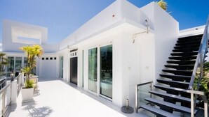 Un edificio moderno con fachada blanca, ventanas grandes y una escalera.