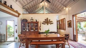 A spacious dining area with a wooden table and chairs, a ceiling fan, and a view of the outdoors. - Hermoso Hideaway (Klaeng)