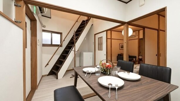 Un espace repas comprenant une table en bois, des chaises et un escalier.
