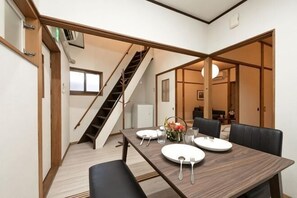 A dining area with a wooden table, chairs, and a staircase. - Kiyomizu Dongurian (Kyoto)