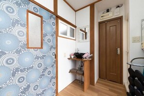 A hallway with patterned wallpaper, a wooden door, a small sink with a mirror, and a shelf with a sink and a towel. - Kiyomizu Dongurian (Kyoto)