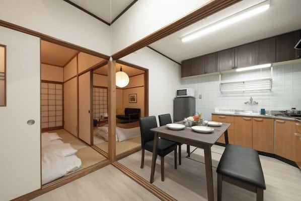 A compact living space with a dining area, kitchenette, and a traditional Japanese room.
