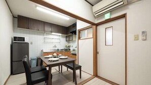 Une cuisine compacte comprenant une table à manger, des chaises, un réfrigérateur et un appareil de climatisation.