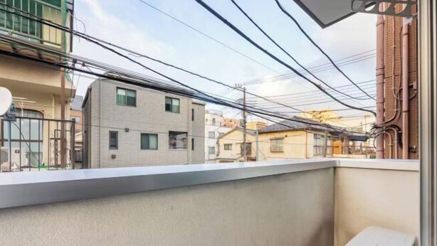 A narrow balcony with a view of neighboring buildings and overhead power lines. - CROWN Umibe (Tokyo)
