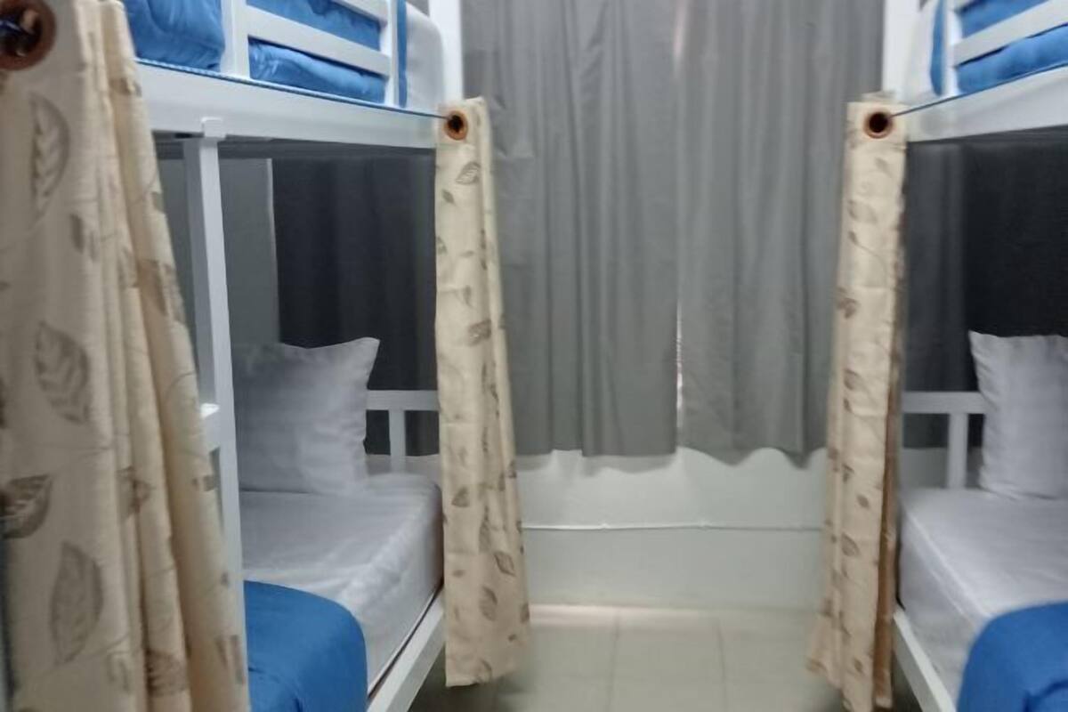 A room with bunk beds, a curtain, and a bed with a pillow.