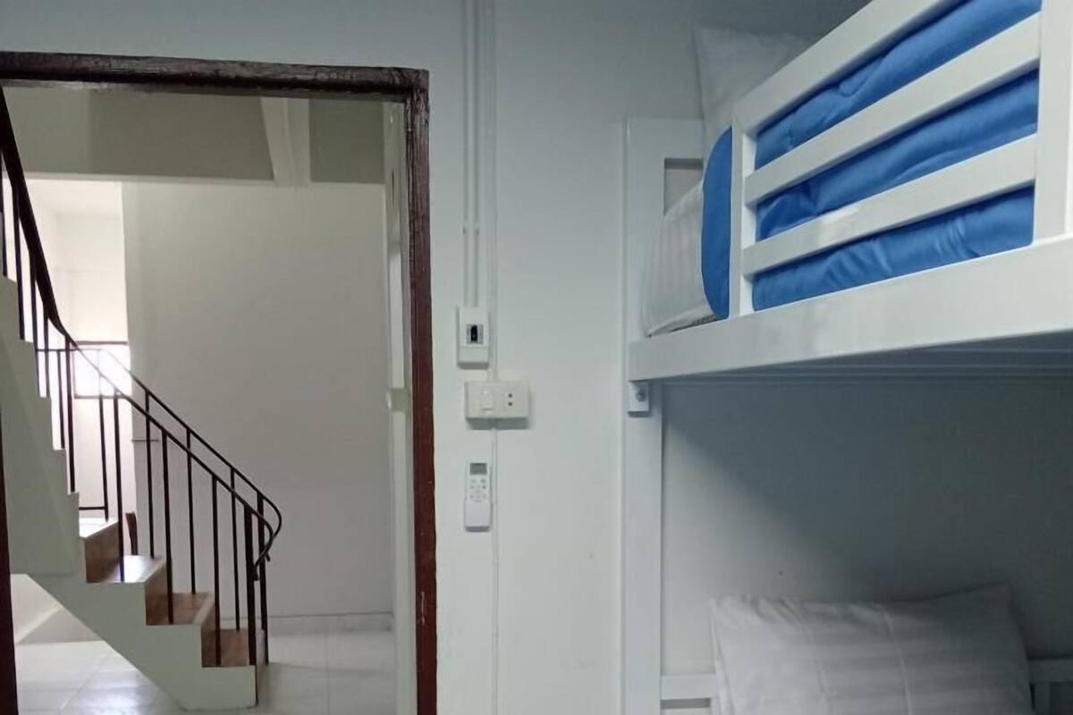 A room with a bunk bed, a staircase, and a door leading to another room.