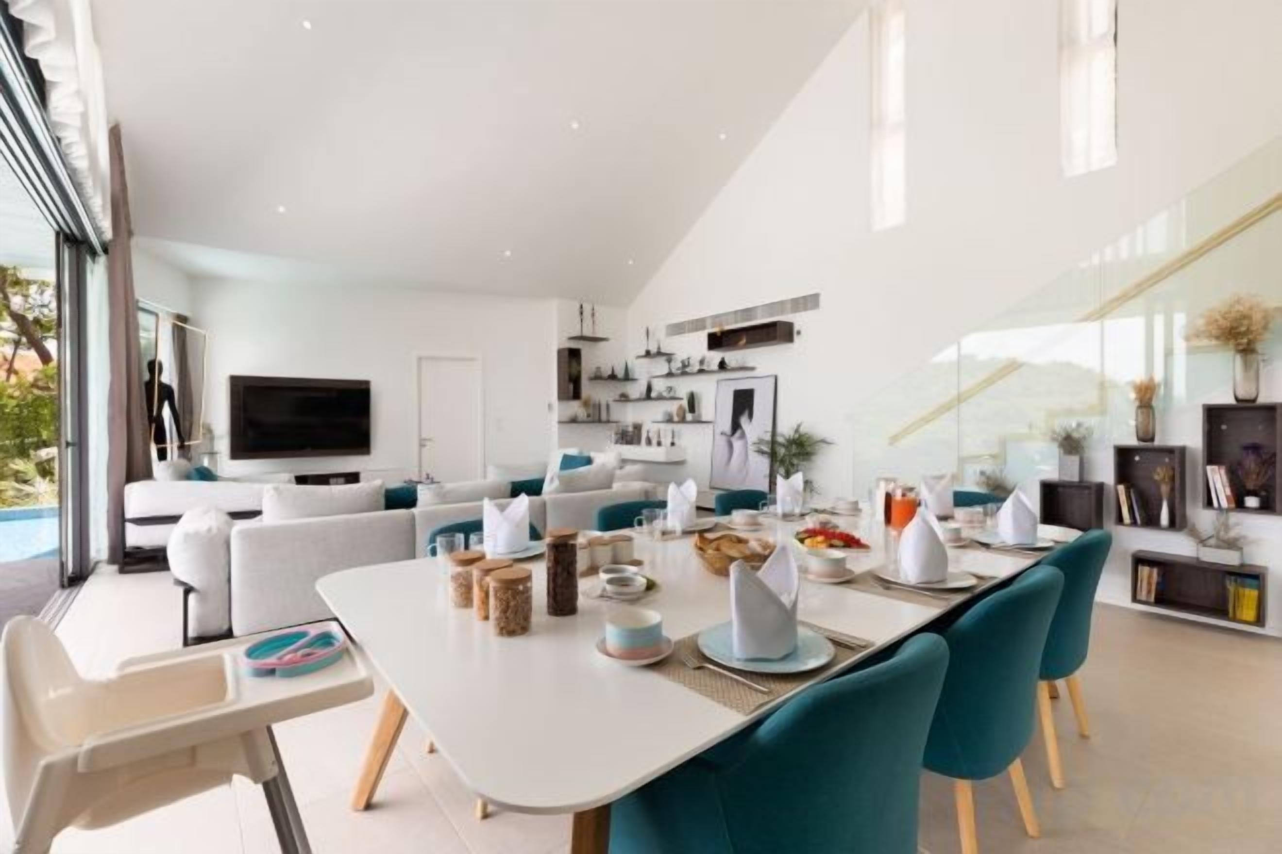 Een moderne woonkamer met een eethoek, een televisie en een keuken op de achtergrond.