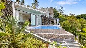 Una casa moderna amb piscina, envoltada de vegetació exuberant i palmeres.