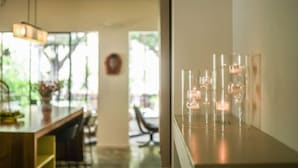 A modern interior with a dining area, a clear glass display case with candles, and a view of the outdoors. - Spacious & Green 3BR Apt w Balcony in City Center (Tel Aviv)
