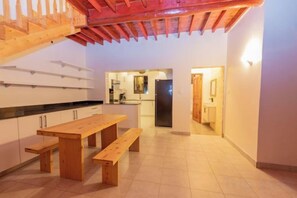 A spacious kitchen with a wooden table and benches, a visible refrigerator, and a tiled floor. - Jandi Diani (Diani Beach)