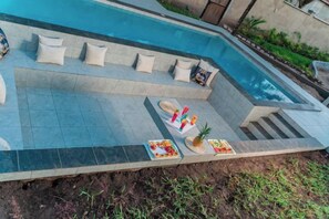 A swimming pool with a built-in seating area and a small table with food and drinks. - Jandi Diani (Diani Beach)