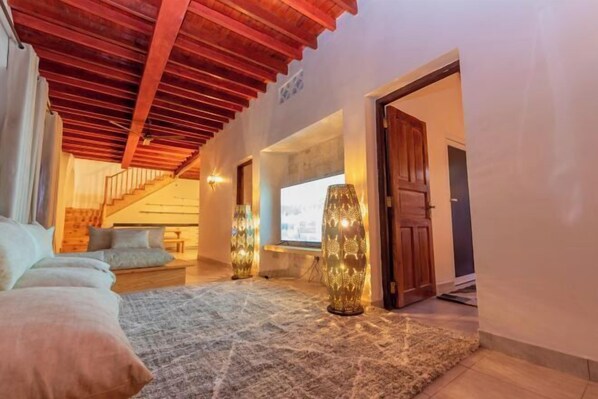 A cozy bedroom with a wooden ceiling, a bed with pillows, a rug, and decorative vases.