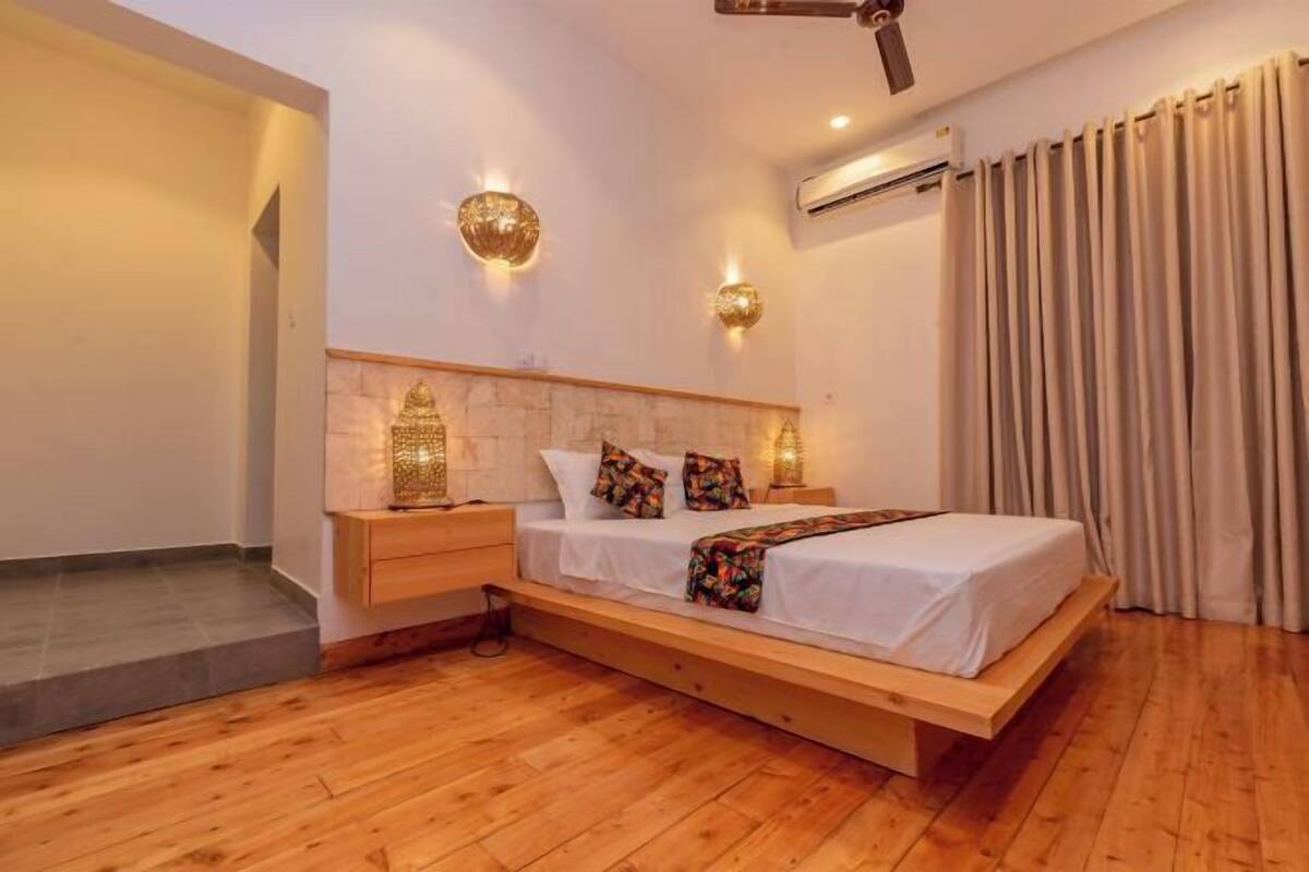 A bedroom with a wooden bed, nightstands, wall sconces, and a ceiling fan.