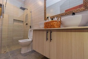 A modern bathroom with a shower, toilet, and vanity with a sink and mirror.