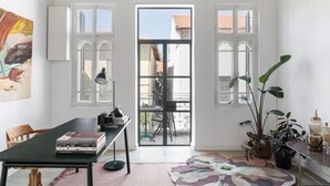 A room with a dining table, chairs, a ceiling fan, a large window, and potted plants. - The Gem of Neve Tzedek Stylish Home (Tel Aviv)