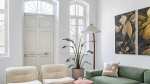 A room with a white door, two chairs, a green sofa, a floor lamp, and a plant. - The Gem of Neve Tzedek Stylish Home (Tel Aviv)