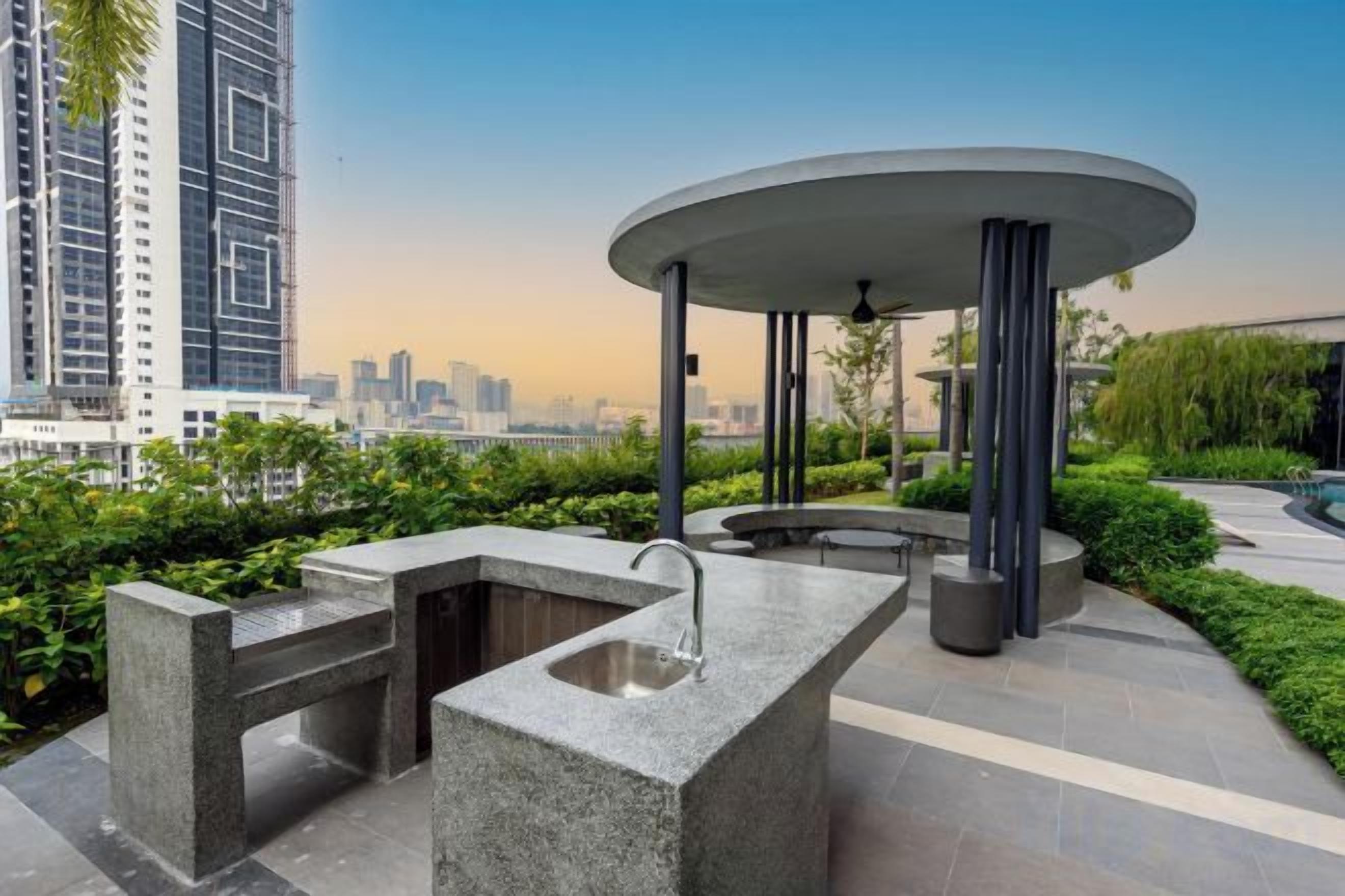 An outdoor area with a circular seating structure, a water feature, and a view of a cityscape.