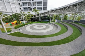 Une cour intérieure ornée de motifs circulaires concentriques, une aire de jeux et un bâtiment à l’architecture moderne.