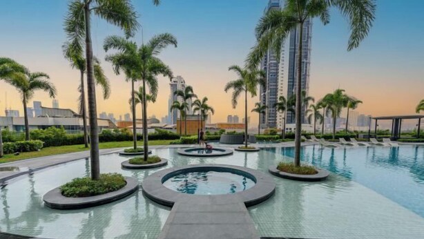 A swimming pool with circular water features and palm trees, surrounded by modern buildings. - Trion@KL by YourSuperhost (Kuala Lumpur)